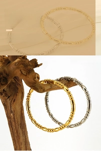 Macro view of gold and silver stainless steel beaded bangles on a natural wood branch