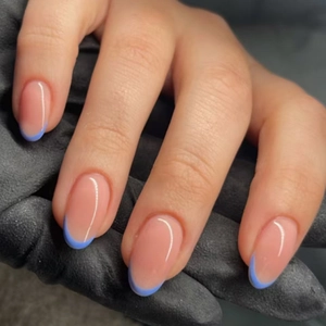 Unghie finte corte ovali con punta French blu su una mano reale con sfondo nero opaco