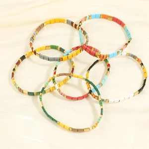 Detail of colorful Bohemian Tila bead bracelets with gold accents on soft satin fabric