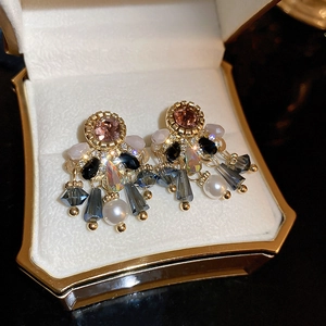 Detail of vintage gold tassel earrings with pink gems and dark crystals in a box