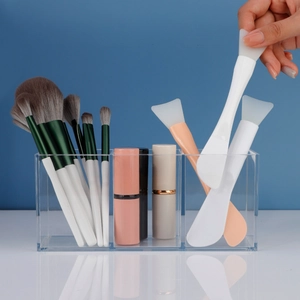 Three-slot acrylic organizer showcasing silicone face mask brushes and makeup storage