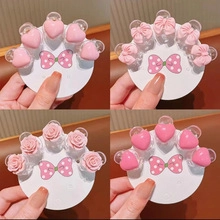 Detail view of pink heart, bow, and rose hair claw clips on white display cards
