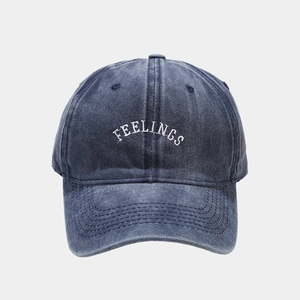 Close-up of white FEELINGS embroidery on vintage washed blue denim baseball cap