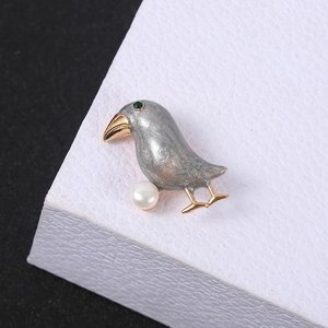 Elegant bird brooch with grey enamel, white pearl and green zircon in gold plating