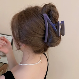 Detail view of a purple matte oversized shark hair clip worn by a model in a cozy setting