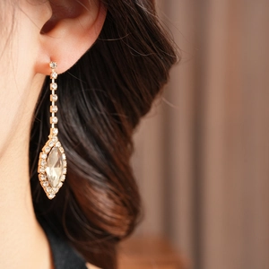 Close-up of elegant gold pear-cut tassel earrings with diamonds worn by a model