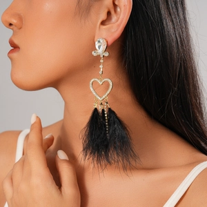 Detail of gold heart earrings with sparkling rhinestones and black feather tassels