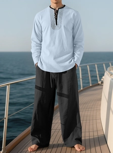 Linen beach set detail featuring light blue henley shirt and black trousers on a yacht