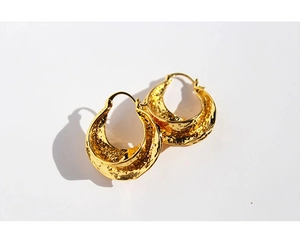 Macro shot of thick gold hoop earrings with irregular hammered metal texture details