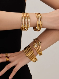 Dettaglio di bracciali rigidi geometrici dorati con zirconi sul braccio