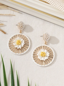 Detail of handmade raffia daisy earrings with pearls on a rustic linen background