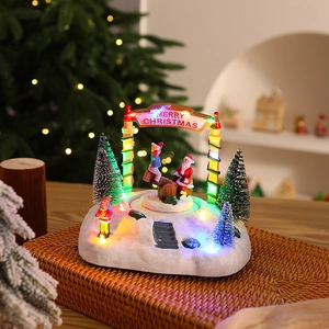 Détail du Père Noël et enfants sur une balançoire avec LED dans une maison de Noël enneigée
