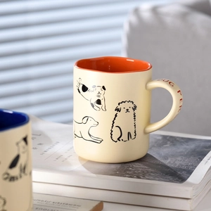 Cute cream ceramic dog person coffee mug with orange interior placed on books