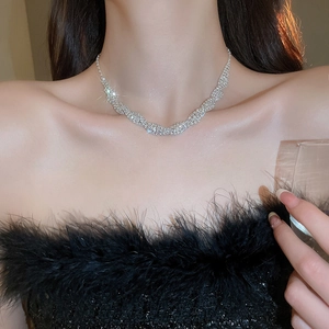 Close-up of a silver-toned wavy necklace with shimmering diamonds on a model's neck
