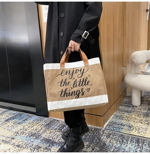 Dettaglio borsa in lino con stampa 'enjoy the little things' e manici in pelle marrone