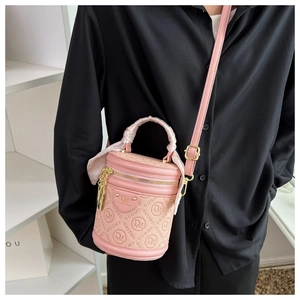 Pink cylinder bucket bag featuring silk scarf handle and embossed logo worn by model