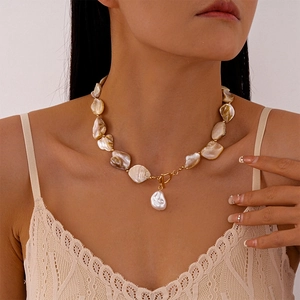 Detail of irregular shell pearl necklace with golden OT clasp shown on female neck