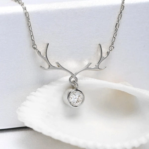 Macro shot of silver reindeer antler pendant with a sparkling round-cut zircon on white conch