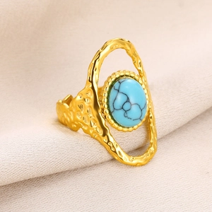 Détail macro d'une bague dorée en forme de soleil avec turquoise et texture martelée