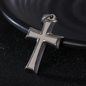 Macro shot of two-tone stainless steel cross pendant with polished edges and matte finish
