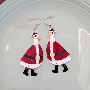 Close-up of acrylic Christmas duck earrings with silver hooks on a green ceramic plate
