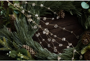 Detailed shot of golden wire beaded garland on festive Christmas pine needles and pinecones