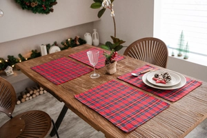 Close-up of four red and blue plaid placemats on a festive wooden Christmas dining table