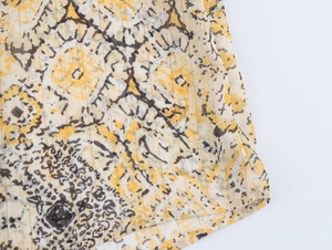 Close-up of yellow and brown abstract floral pattern on lightweight striped shirt fabric