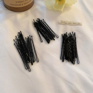 Détail de barrettes à cheveux en métal noir sur fond de tissu en lin blanc