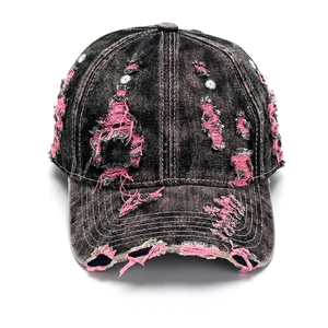 Detailed view of washed denim baseball cap with distressed pink frayed rip details