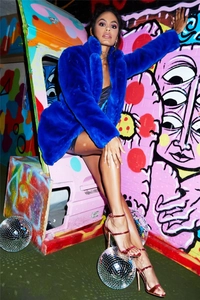 Détail d'un manteau en fausse fourrure bleu roi avec boules disco et fond graffiti