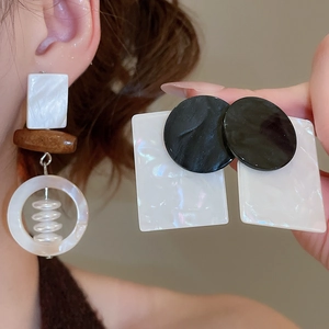 Detail of geometric earrings featuring shell, wood beads, and acetate in retro style