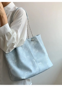 Light blue textured tote bag with silver chain strap shown in a side view on shoulder