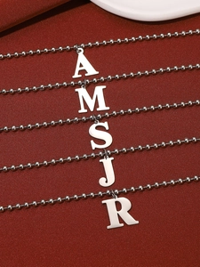 Detailed macro view of silver initial pendants A M S J R on polished beaded chain link