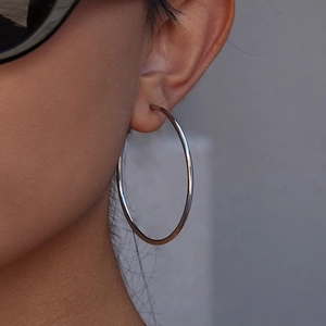 Close-up of a silver stainless steel C-shaped hoop earring worn on a model's ear