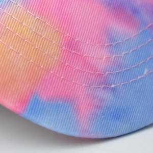 Macro view of tie-dye cotton baseball cap brim with colorful gradient and reinforced stitching