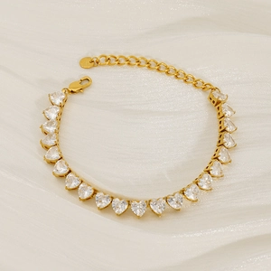 Gold heart zircon tennis bracelet on white silk background with adjustable chain
