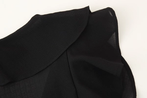 Close-up of the delicate black chiffon fabric and ruffled hem detailing on the dress