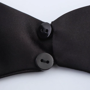 Close-up of black satin halter mini dress featuring glossy fabric and button detail