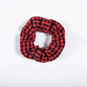 Close-up of red and black buffalo plaid fabric scrunchie with soft elastic texture