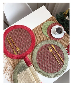 Red and green Christmas woven placemats set with golden cutlery on a festive white table