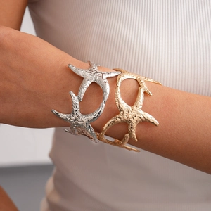 Detail of starfish open cuffs in gold and silver finish with hammered metal texture