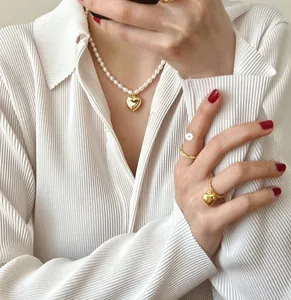Detail view of 925 sterling silver heart pearl necklace and gold rings set on model