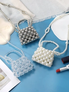 Close-up of three mini handmade beaded handbags in silver, pearl white and clear crystal