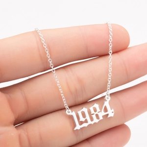 Close-up of a silver 1984 birth year pendant necklace held to show delicate chain detail