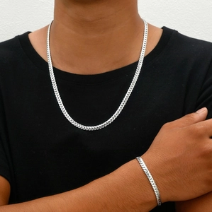 Polished silver cuban chain necklace and bracelet jewelry set shown on a model