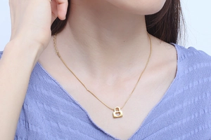Close-up of a gold heart-shaped padlock necklace pendant on a model's neck