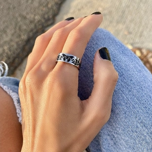 Detail of silver titanium steel ring with black butterfly pattern worn on hand