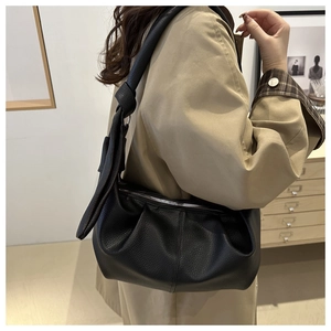 Detail shot of black wrinkled leather hobo bag showing soft lychee texture and shoulder strap