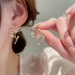 Close-up of elegant gold flower earrings with clear zircon crystals on model ear